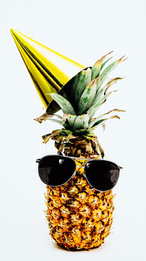 Fun pineapple wearing stylish sunglasses and party hat – trendy summer sunglasses concept