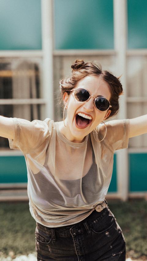 Happy woman wearing fashionable round sunglasses with UV protection outdoors